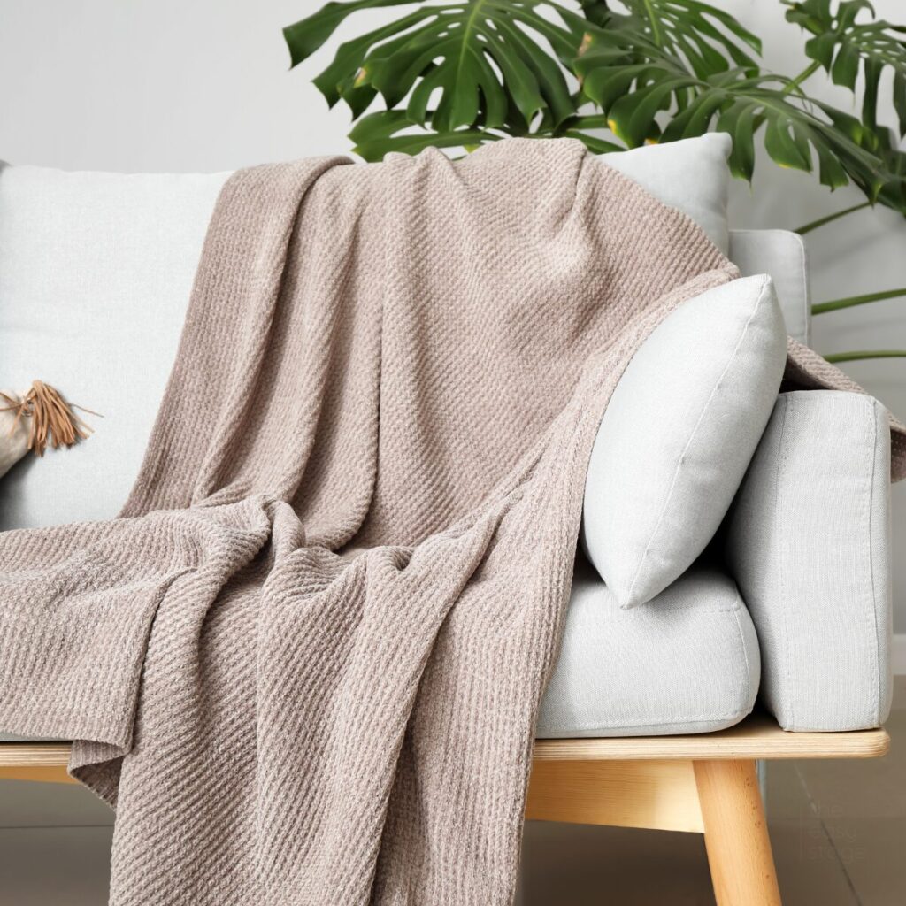 Lightweight cotton throw draped over a neutral sofa in a bright summer living room.