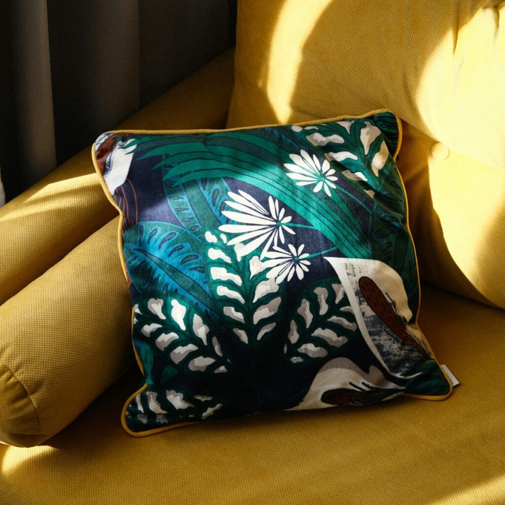 Tropical and botanical cushions in vibrant greens and florals on a contemporary couch.