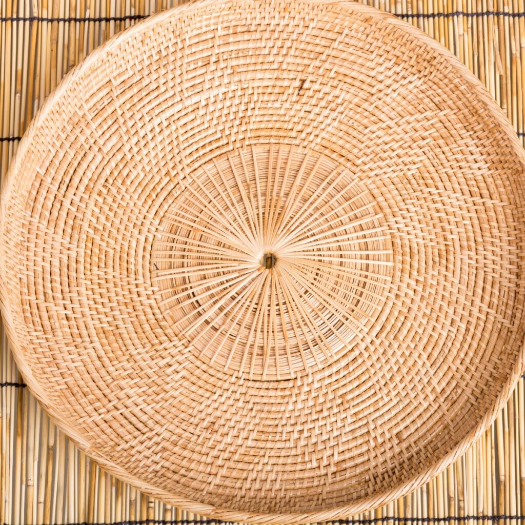 Decorative rattan tray styled on a wooden coffee table with summer accessories.