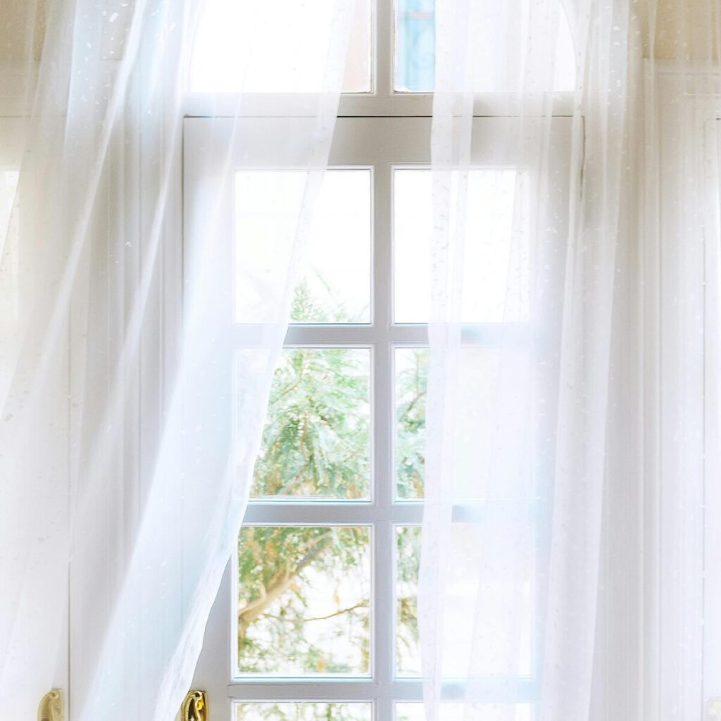 Sheer white curtains allowing natural light to flood a sun-filled room.